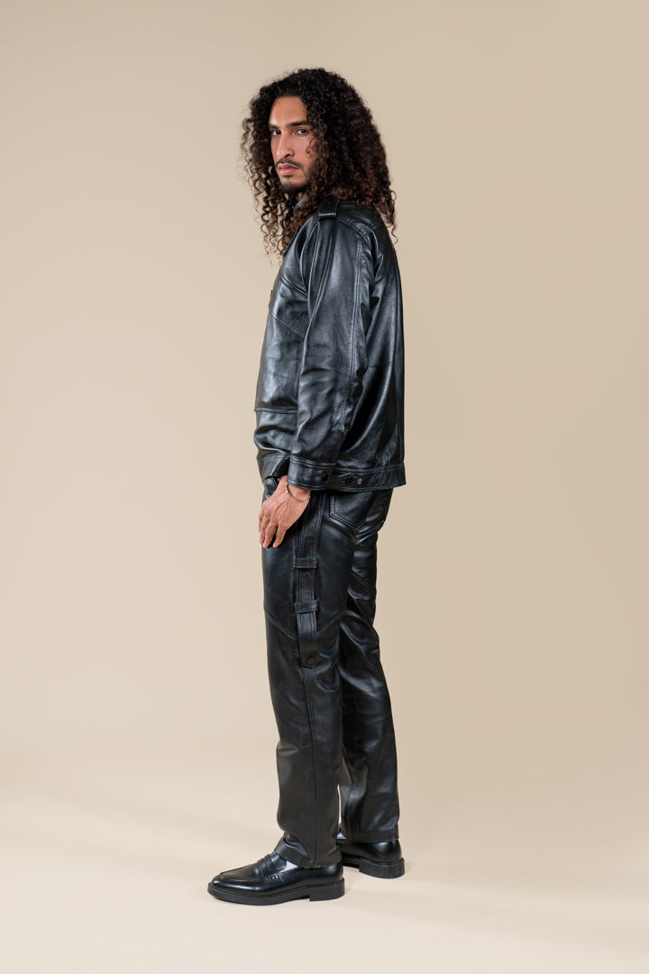 Pantalon Amnay Numidie en cuir noir, vue de profil porté par un modèle, avec poches cargo et détails de couture.