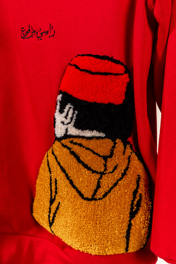 Détail du motif tufting artisanal représentant un personnage sur le pull Tarbouche Numidie rouge.