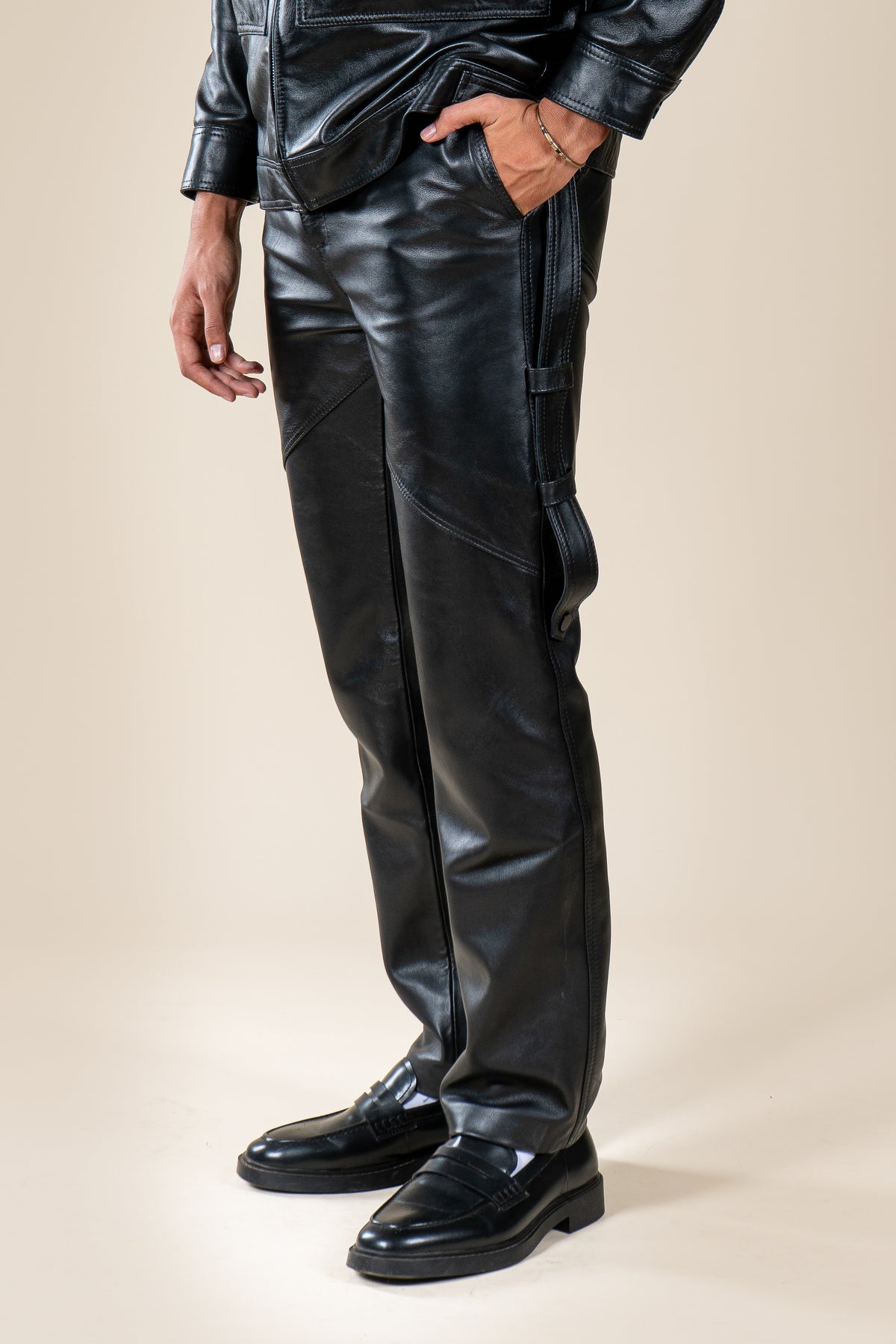 Pantalon Amnay Numidie en cuir noir, vue rapprochée des poches latérales, des sangles et des coutures décoratives.