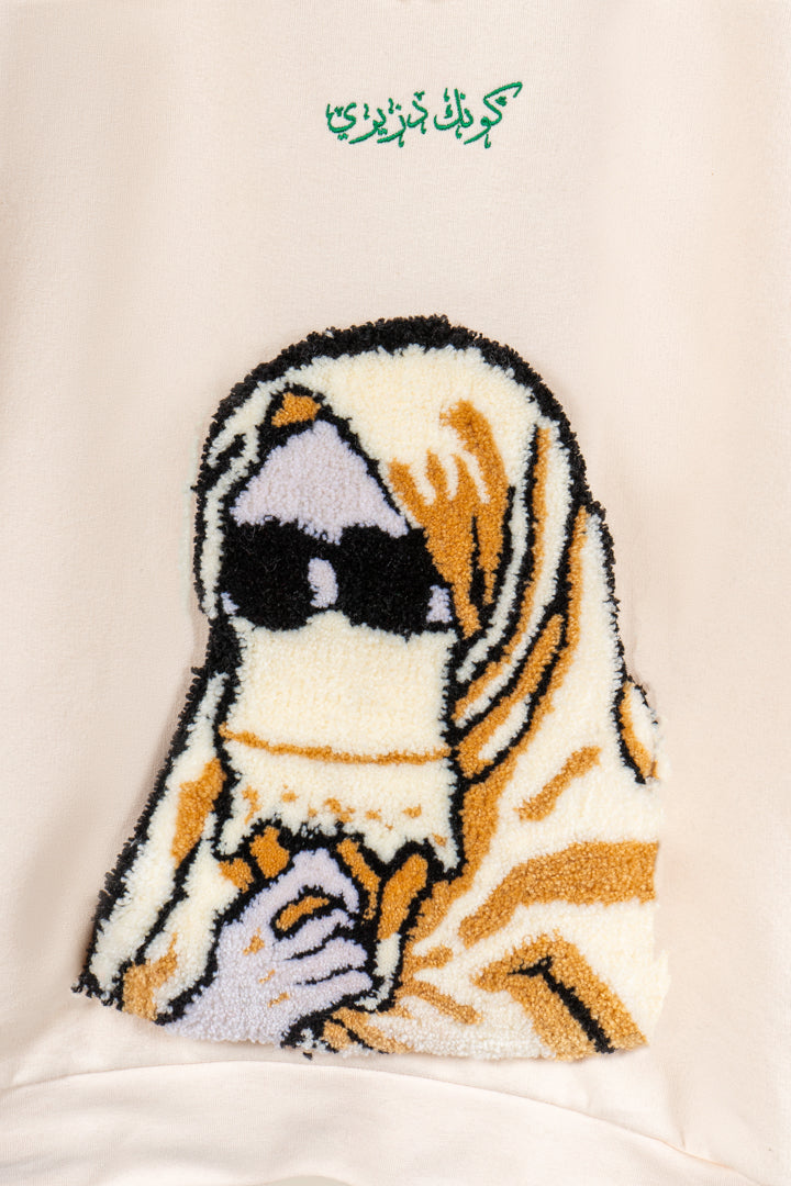 Détail du motif tufting artisanal représentant un femme en haik sur le pull Numidie beige.