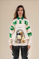Pull Numidie beige avec lettres vertes, col vert et motif tufting artisanal représentant un personnage, porté par une femme.