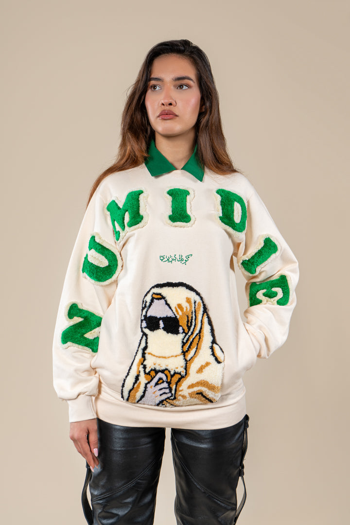 Pull Numidie beige avec détails verts et motif tufting artisanal, porté par une femme, vue de trois-quarts.