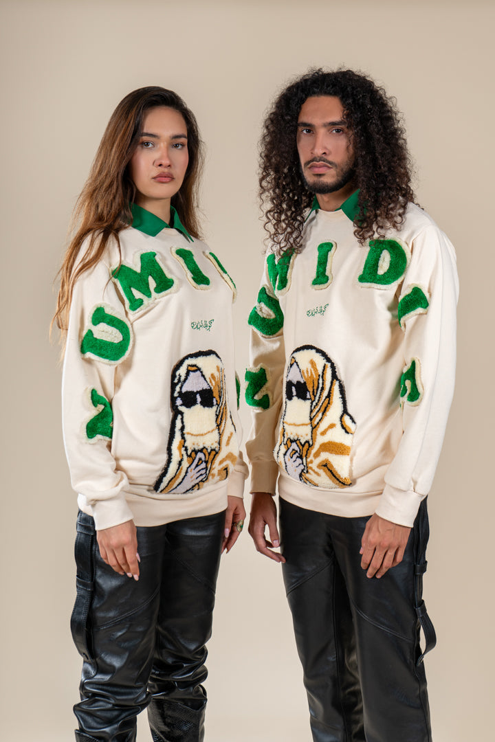 Pulls Numidie beiges avec lettres vertes et motifs tufting artisanaux, portés par un homme et une femme.