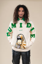 Pull Numidie beige avec lettres vertes et motif tufting artisanal, porté par un homme.