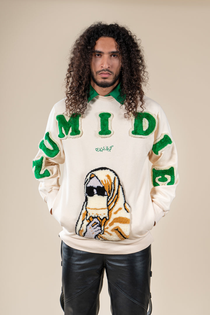 Pull Numidie beige avec lettres vertes et motif tufting artisanal, porté par un homme.