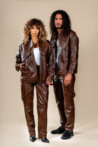 Pantalon Amnay en cuir marron porté par deux mannequins, femme et homme.