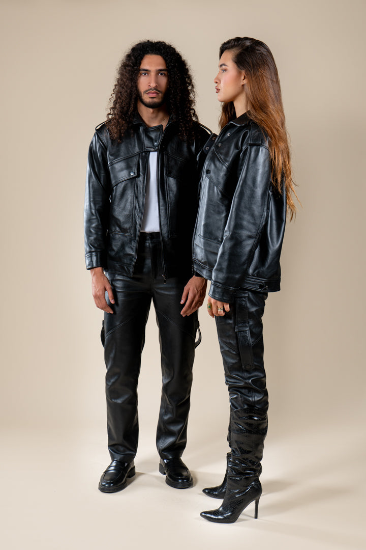 Pantalon Amnay Numidie en cuir noir, porté par deux modèles, mettant en valeur sa coupe et ses détails.
Veste Azir Numidie en cuir noir portée par un homme et une femme, présentation de la collection en cuir.