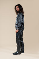 Pantalon Amnay Numidie en cuir noir, vue de profil porté par un modèle, avec poches cargo et détails de couture.