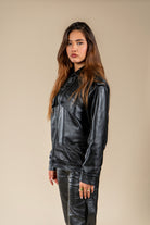 Veste Azir Numidie en cuir noir portée par une femme, vue de face, avec poches à rabat et coupe structurée.