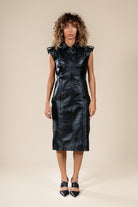 Robe Tihya Numidie en cuir noir, coupe midi ajustée, col chemise, poches à rabat et finitions structurées.
