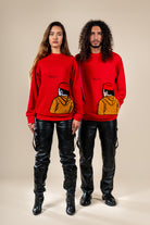 Pantalon Amnay Numidie en cuir noir, porté par deux modèles avec des pulls rouges, mettant en valeur sa coupe et ses détails.