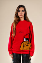 Pull Tarbouche Numidie rouge avec motif tufting artisanal représentant un personnage, porté par une femme.