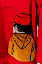 Détail du motif tufting artisanal représentant un personnage sur le pull Tarbouche Numidie rouge.