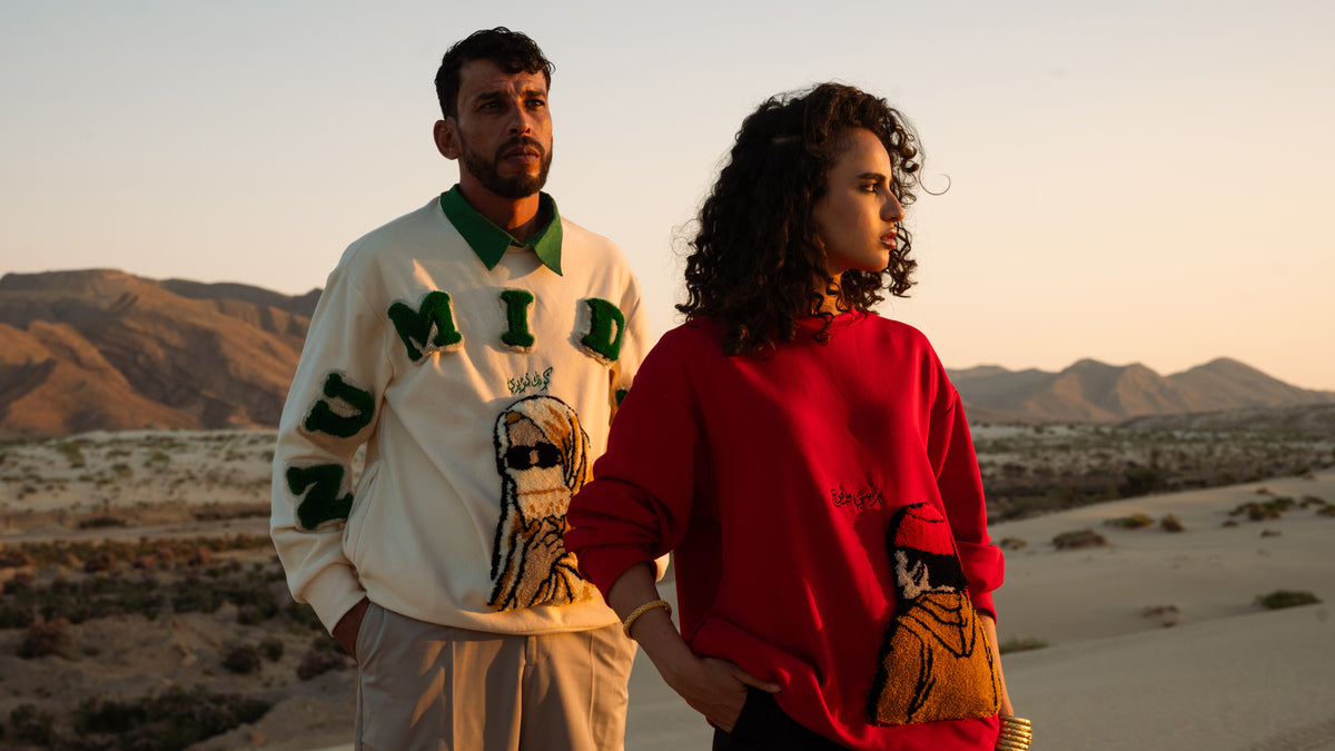 Pull Numidie beige et Pull Tarboucha rouge en tufting artisanal, portés par deux modèles Numidie dans un paysage désertique algérien.