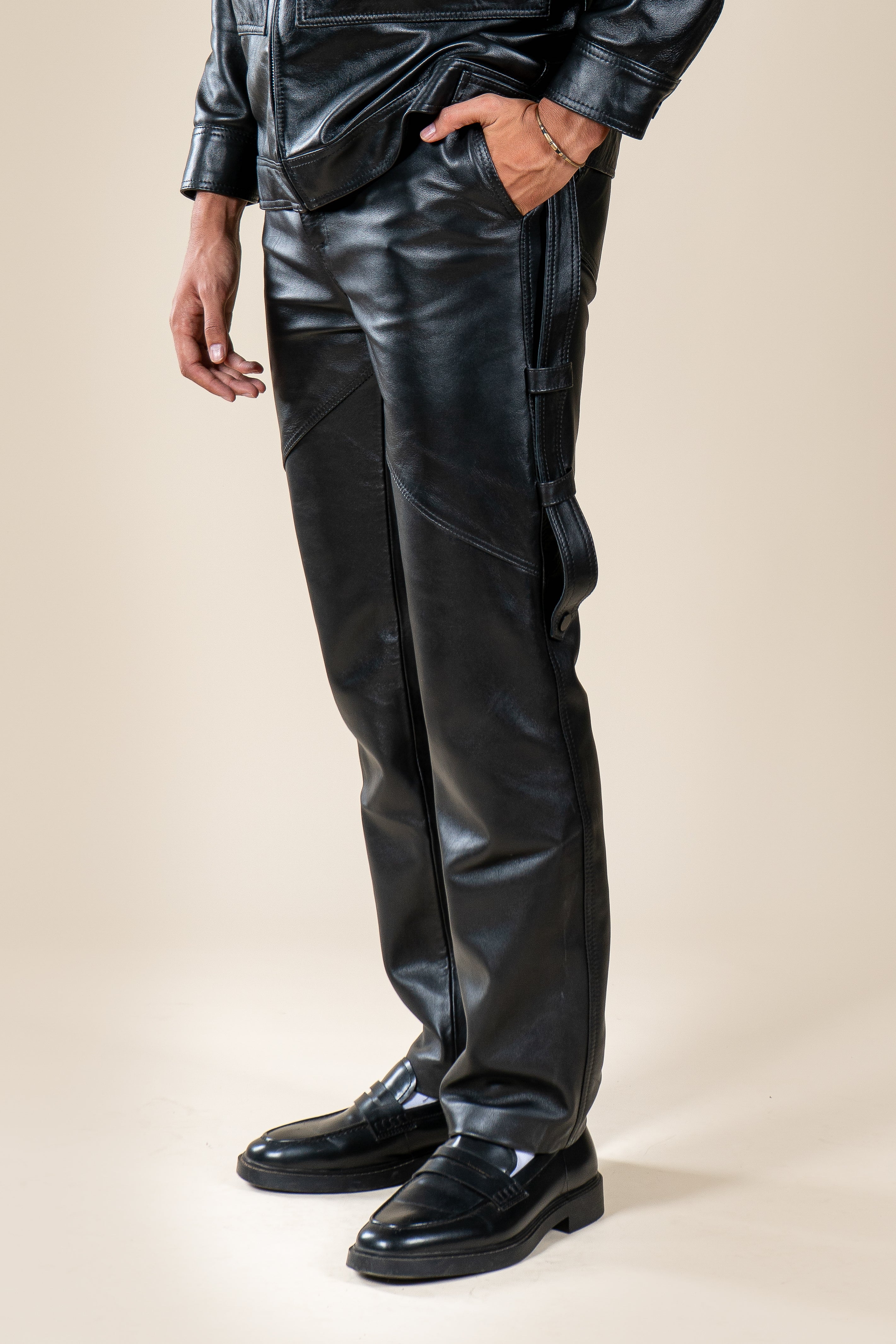 Pantalon Amnay Numidie en cuir noir, vue rapprochée des poches latérales, des sangles et des coutures décoratives.