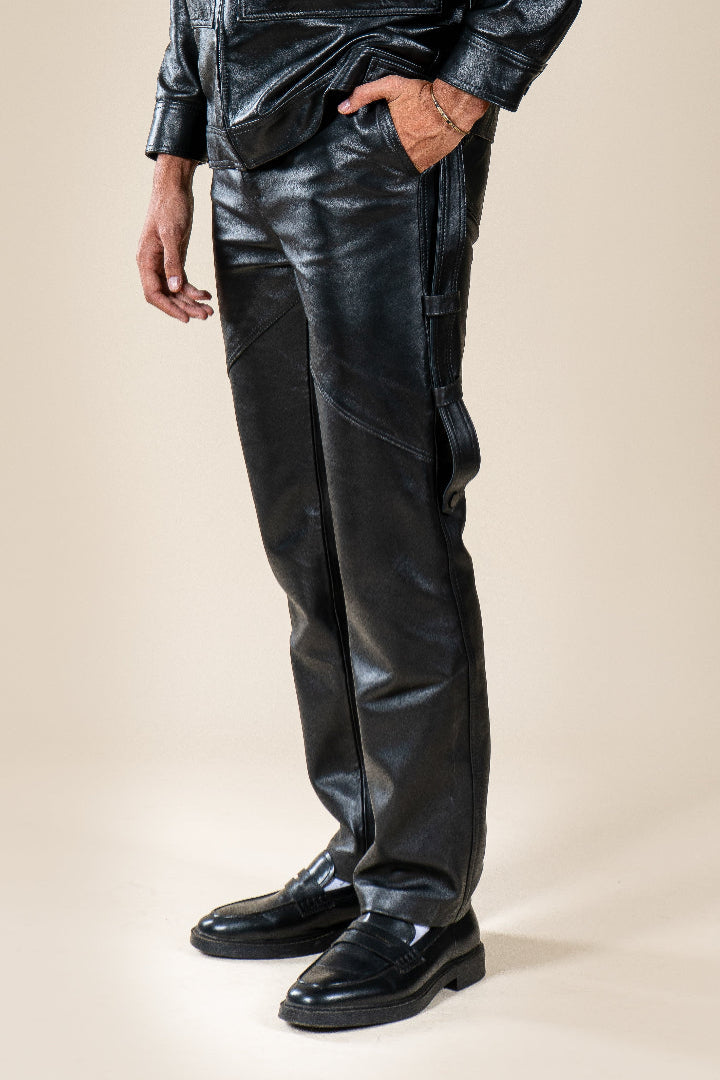 Pantalon Amnay Numidie en cuir noir, vue rapprochée des poches latérales, des sangles et des coutures décoratives.